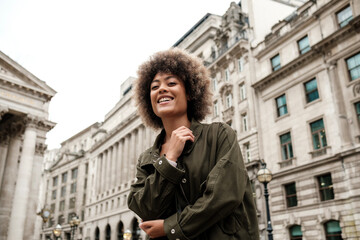 Portrait of smiling mixed race woman in front of building.