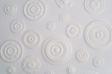 A collection of artistic white circular bas-relief sculptures with various patterns is arranged...