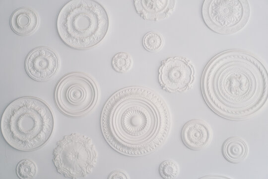 A collection of artistic white circular bas-relief sculptures with various patterns is arranged against a pristine white backdrop, showcasing a minimalist aesthetic with an emphasis on textures