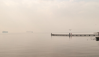 Where sea meets sky, foggy serenity on the pier, wide view of a pier scene
