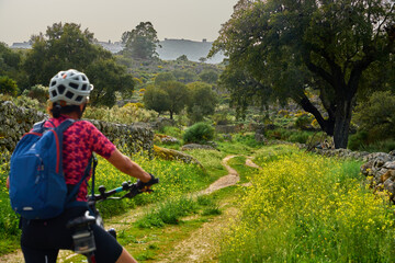 active senior woman cycling with her electric mountain bike in the rough landscape of National Parc Serra de São Mamede near Marvao in central Portugal, Europe - 795369894