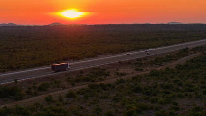 AERIAL: Scenic view of cargo truck driving along highway on sunny summer evening