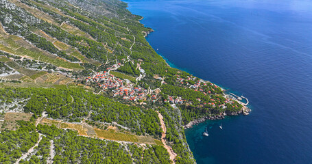 AERIAL: A quaint coastal town on Hvar island overlooks the calm Dalmatia waters - obrazy, fototapety, plakaty