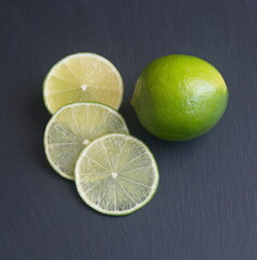 Sliced lime fruit, green citrus fruit, Bear lime, Tahiti lime, on dark grey stone background