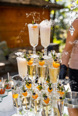 A stack of champagne glasses with fruit garnishes on top. The glasses are arranged in a pyramid shape