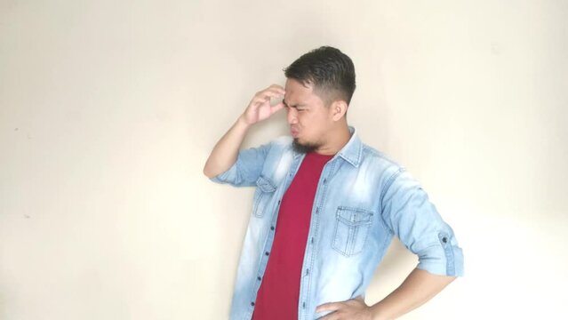 Asian adult man with confused and dizzy expression while holding his head