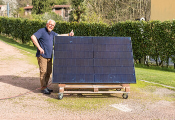 Senior man with photovoltaic solar panel in the garden. 