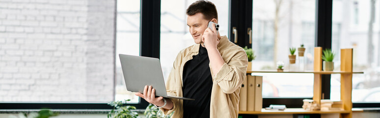 A handsome businessman with a prosthetic leg efficiently multitasking with a cell phone and laptop.