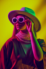 Chic look with young woman, model wearing retro-futuristic round sunglasses, hat and dress against...