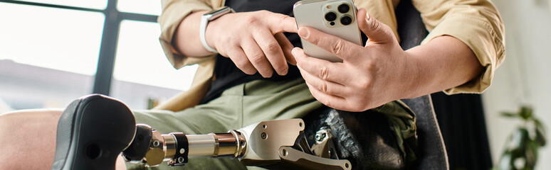 Businessman with prosthetic leg sits holding phone.