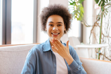 Cheerful, authentic, smiling African American woman with curly hair communicates using sign language