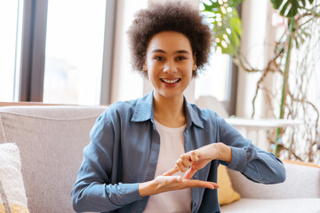 Portrait authentic, smiling African American woman with curly hair communicates using sign language