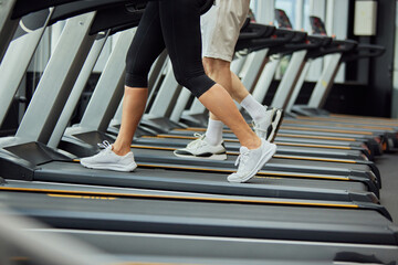 Cardio training to fat burning. Cropped portrait of senior man's and woman's legs on treadmill in...