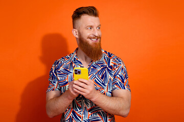 Photo of cute dreamy guy dressed print shirt typing modern device looking empty space isolated...