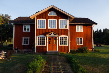 rotes Haus in Schweden bei Sonnenuntergang auf grüner Wiese