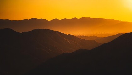 Fototapeta na wymiar orange and yellow sunset above layers of mountains