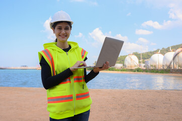 Female chemical engineer doing inspection work at a chemical storage tank on the seaside.