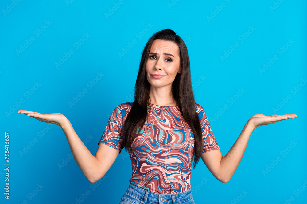 Poster Photo portrait of pretty young girl hold compare empty space skeptical wear trendy colorful clothes isolated on blue color background