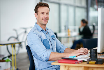 Portrait, smile and business man typing on computer in office at startup, company or workplace for...