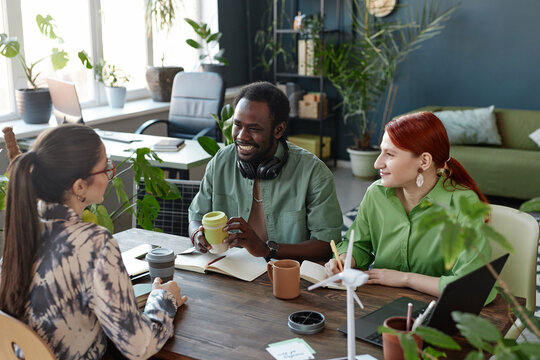 Diverse creative  business team enjoying work at meeting table in green eco friendly office with plants 