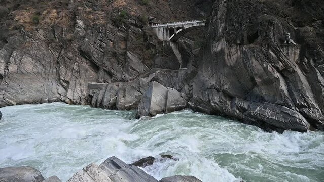 An old bridge opposite the landscape of Tiger Leaping Gorge in Yunnan province of China. Scenic spot where a tiger is said to have leaped across the river, thus giving the gorge its name.