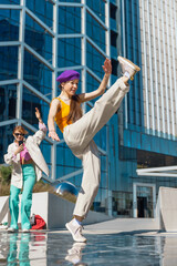 Vertical Screen: Young And Stylish Female Hip Hop Dancer Freestyling On City Street In the Circle Of Fashionable Friends. Group Of Young People Supporting Professional Performer, Filming On Smartphone