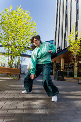 Vertical Screen: Young And Stylish Female Hip-Hop Dancer Freestyling On City Street Among Tall Buildings. Street Style Performer Doing Improvisation. Caucasian Woman Practicing New Choreography.