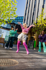 Vertical Screen: Fashionable Young Woman Wearing Pink Outfit Voguing On City Street In Circle Of Stylish Friends. Group Of Young People Supporting Female Vogue Performer, Filming Her On The Smartphone