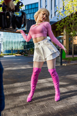 Vertical Screen: Behind The Scenes Photo With Young Female Vogue Dancer Performing Her Choreography On Modern City Street. Operator Filming Caucasian Woman Voguing With Professional Camera.
