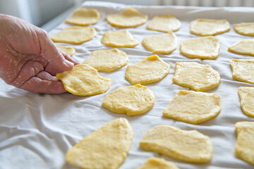 Side view in close up of a woman making homemade noodle dough in kitchen with natural backlight, home atmosphere.