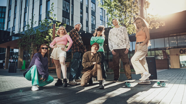 Vibrant Group Of Young Adults Showcasing Diverse Street Styles And Dynamic Poses In An Urban Setting, Reflecting Youth Culture, Friendship, And The Joy Of Dance Under The Afternoon Sun.