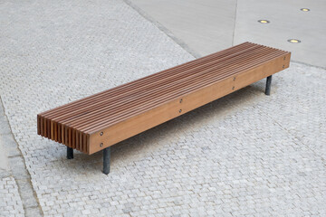 A wooden bench on the street offers modern design and functionality for outdoor seating, urban...