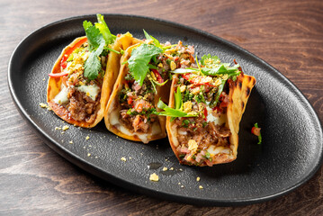 Delicious, vibrant tacos with succulent meat and fresh herbs served on a dark plate, capturing a delightful culinary experience