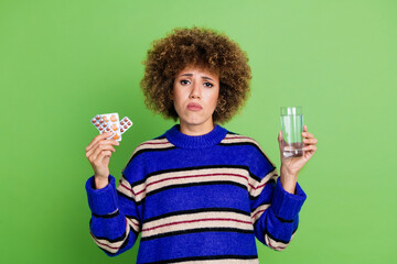 Photo of sad upset woman wear blue striped trendy clothes hold pills feel bad isolated on green color background - obrazy, fototapety, plakaty