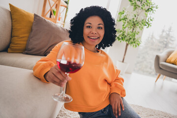 Photo portrait of lovely young lady sit floor enjoy wine dressed casual orange clothes cozy day light home interior living room - obrazy, fototapety, plakaty
