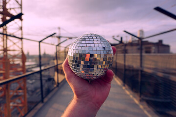 Cropped hand holding a disco ball outdoors
