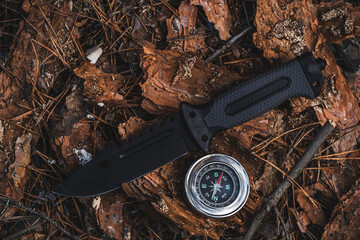 Compass and knife on ground in forest. Adventure and travel concept.