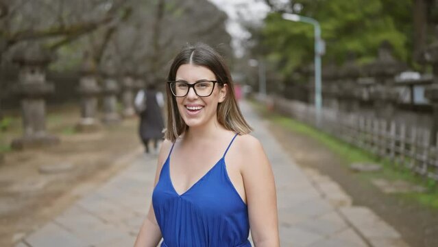Smiling beautiful hispanic woman in glasses posing confidently at ueno park temple, radiating joy and success