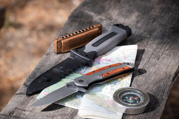Knife, compass and map on a wooden table. Travel concept.