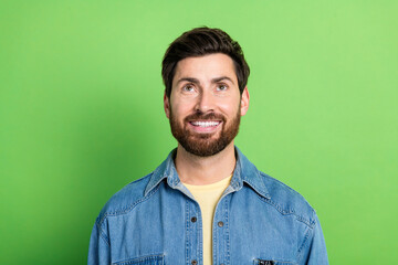 Photo of cheerful positive guy dressed jeans shirt smiling looking up empty space isolated green...