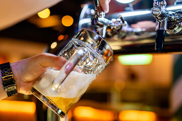 Dynamic scene in a pub with a bartender pouring frothy beer from a tap into a clear mug,...