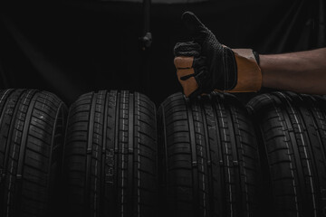 Closeup view of car tires with man hand in leather glove.