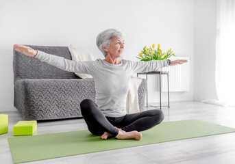 Calm Home Exercises In A Bright Room, A 70-Year-Old Woman Practices Yoga