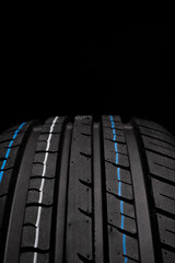 Car tires on black background, closeup of tread, selective focus.