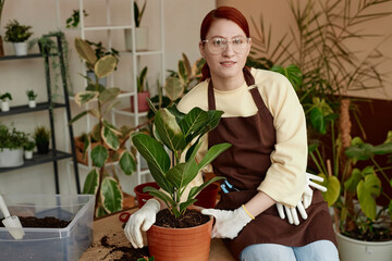 Portrait of red haired young woman looking at camera while enjoying gardening at home, copy space