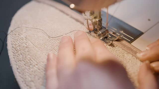Needle for sewing machine in motion. The close-up of the sewing machine needle quickly moves up and down. The seamstress sews fabric in the sewing workshop. The process of sewing the fabric.