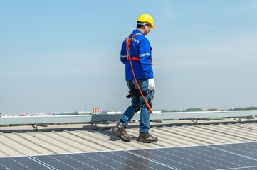 A solar panel installer walks across a roof inspecting the panels.