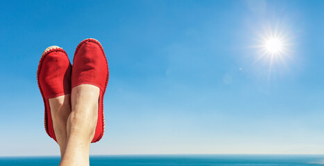 Damenbeine mit Roten Stoffschuhen vor blauem Himmel