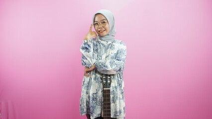 Indonesian Muslim woman guitar on a pink background