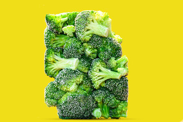 Frozen Organic broccoli florets in a rectangular shape in one piece on yellow isolated Background....